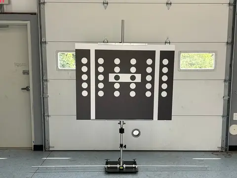 A camera calibration target board set up on a stand in front of a garage bay door