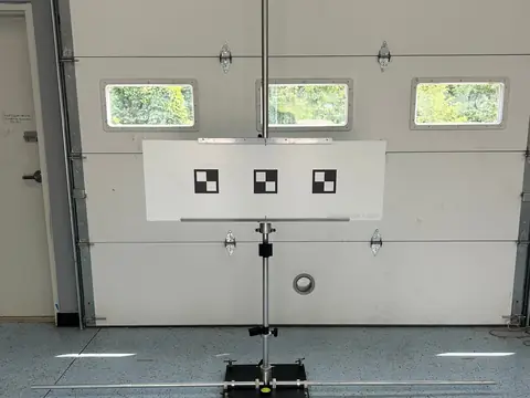 A calibration target with three checkered squares on a stand in the Impex service bay