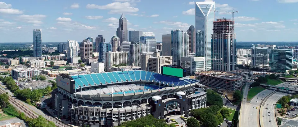 The Uptown Charlotte, NC, skyline and the football stadium under a blue sky with white clouds