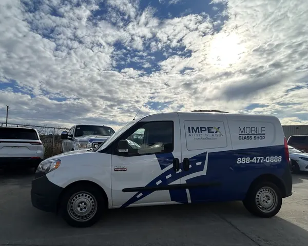 An Impex Auto Glass mobile glass van parked in a lot under a bright, cloudy sky