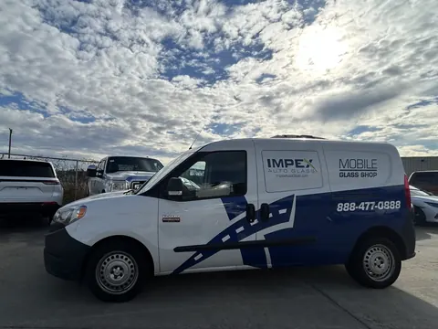 An Impex Auto Glass mobile glass van parked in a lot under a bright, cloudy sky