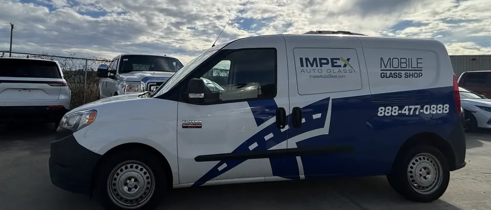 An Impex Auto Glass mobile glass van parked in a lot under a bright, cloudy sky